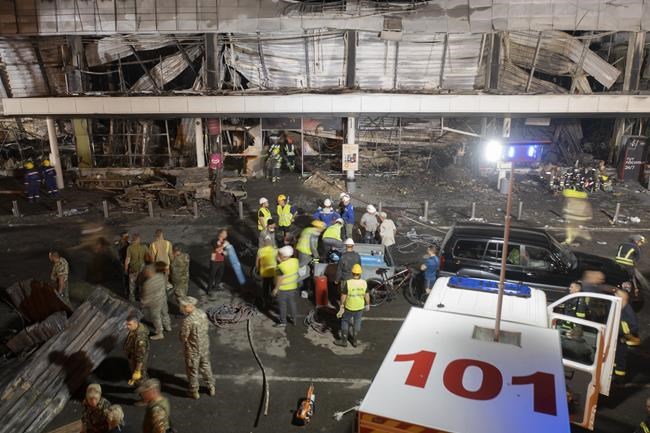 Ukrainian State Emergency Service firefighters work to take away debris at a shopping center burned after a rocket attack in Kremenchuk, Ukraine, Monday, June 27, 2022. Residents of the quiet, riverside city of Kremenchuk are reeling in the wake of a Russian airstrike that obliterated a shopping mall and killed at least 18. With dozens still missing, psychologists are working with families to help them through their grief and toward acceptance that they may never find their loved ones. (AP Photo/Efrem Lukatsky)
