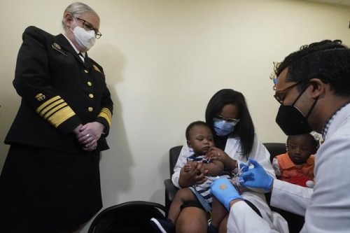 Pediatrician Emy Jean-Marie, center, holds her nine-month-old son Adedeji Adebayo, Emiola Adebayo, 3, on her lap as Dr. Nizar Dowla, right, administers a vaccine while        Department of Health and Human Services Assistant Secretary for Health, Admiral Rachel Levine, left, looks on, Tuesday, June 28, 2022, at the Borinquen Health Care Center in Miami. Florida is the only state that didn't pre-order the under-5 vaccine, and state Surgeon General Joseph Ladapo has recommended against vaccinating healthy children. (AP Photo/Wilfredo Lee)