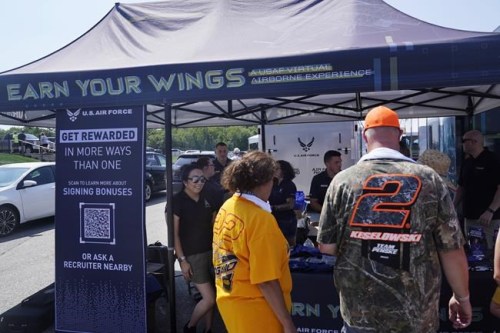 Racing fans stop at the U.S. Air Force recruiting tent prior to a NASCAR race at the New Hampshire Motor Speedway, Sunday, July 17, 2022, in Loudon, N.H. These are tough times for military recruiters.  All services are having problems finding young people who want to join and can meet the physical, mental and moral requirements.  Recruiters are offering bigger bonuses and other incentives to those who sign up. And they are seizing on the boost that Hollywood may offer – such as the buzz over Top Gun. (AP Photo/Charles Krupa)