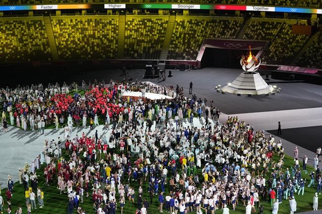 FILE - Athletes arrive for the closing ceremony in the Olympic Stadium at the 2020 Summer Olympics, Sunday, Aug. 8, 2021, in Tokyo, Japan. The Tokyo Olympics survived the COVID-19 postponement, soaring expenses and some public opposition. A year later, the costs and benefits are as difficult to untangle as the Games were to pull off. (AP Photo/Lee Jin-man, File)