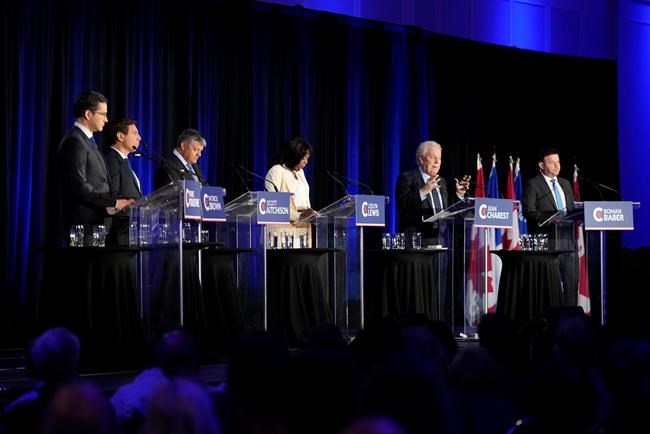 The Conservative Party of Canada is pushing ahead with a third leadership debate, telling members to tune in Aug. 3. Conservative leadership hopeful Jean Charest, second right, speaks as Pierre Poilievre, left to right, Patrick Brown, Scott Aitchison, Leslyn Lewis, and Roman Baber look on during the Conservative Party of Canada French-language leadership debate in Laval, Quebec on Wednesday, May 25, 2022. THE CANADIAN PRESS/Ryan Remiorz