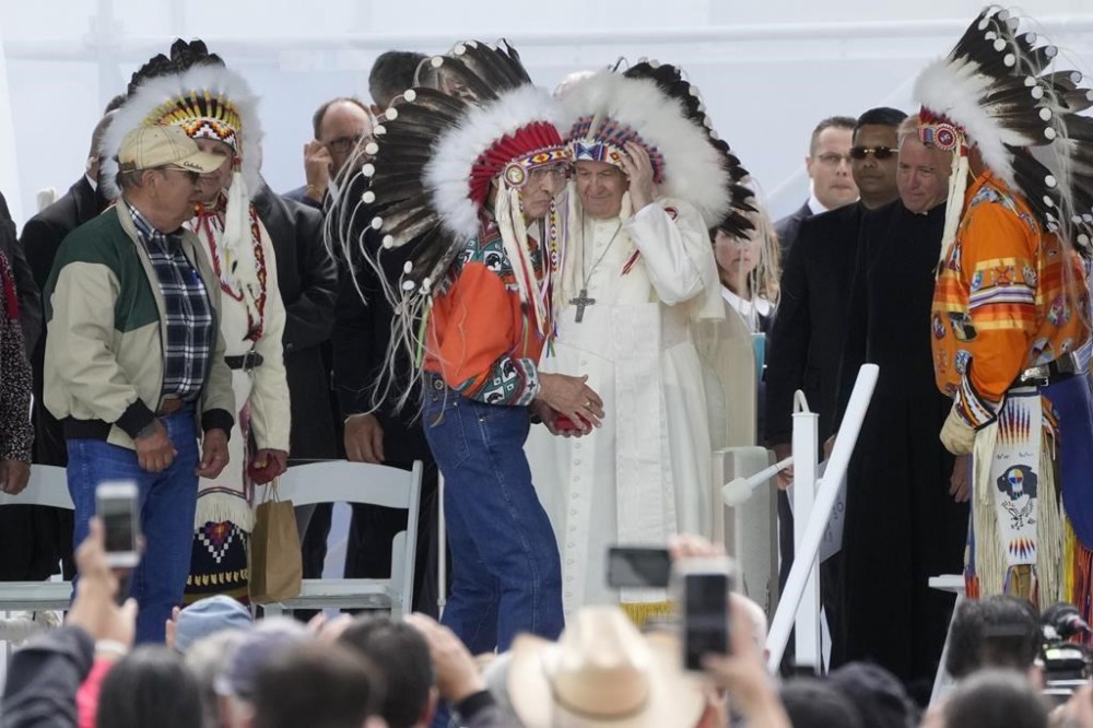 Pope Francis puts on an indigenous headdress during a meeting with indigenous communities, including First Nations, Metis and Inuit, at Our Lady of Seven Sorrows Catholic Church in Maskwacis, near Edmonton, Canada, Monday, July 25, 2022. Pope Francis begins a