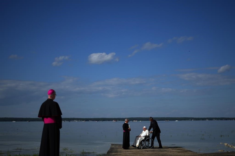 Pope Francis gets water from the lake after blessing it during the annual pilgrimage event in Lac Ste. Anne, Alta., Tuesday, July 26, 2022. THE CANADIAN PRESS/Nathan Denette