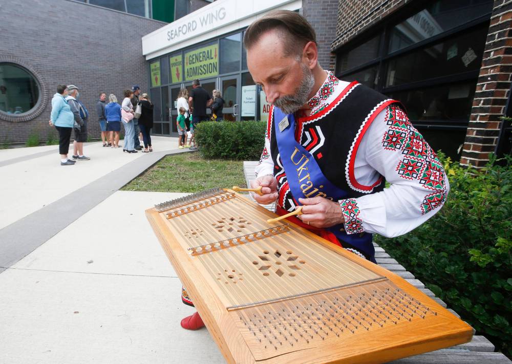 Myles Burdeniuk plays the tsyvaly as people wait to enter the pavilion. (John Woods / Winnipeg Free Press)