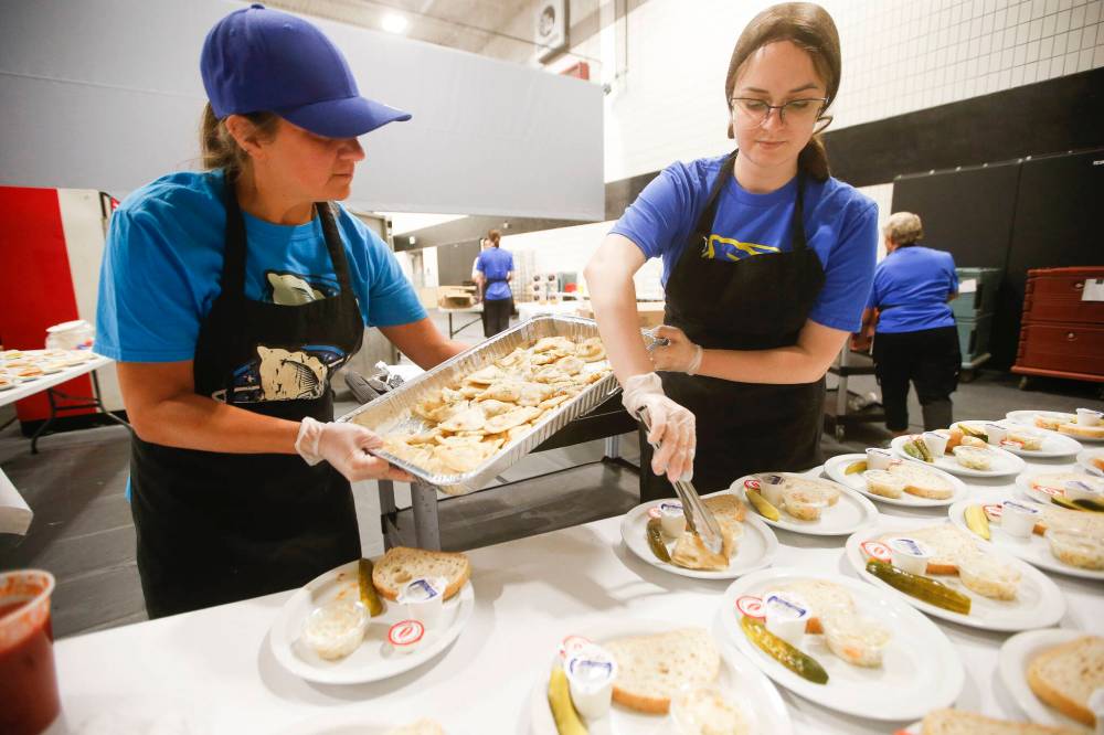 ennifer Boreski, left, and Sofiya Polishchuk, a recent newcomer from Kyiv, serve food at the pavilion. (John Woods / Winnipeg Free Press)