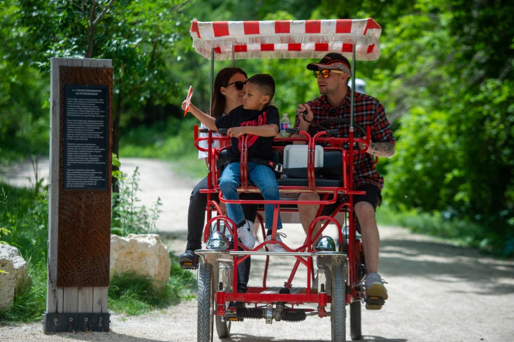 ETHAN CAIRNS / WINNIPEG FREE PRESS
A child waves a Canada flag while biking with family at the A New Day Ceremony at The Forks Plaza in Winnipeg, Manitoba on Friday, July 1, 2022