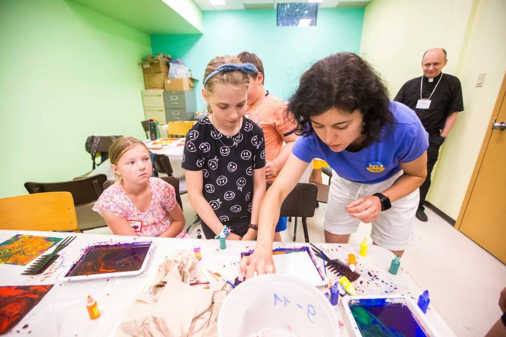 MIKAELA MACKENZIE / WINNIPEG FREE PRESS Day camp leader Lesia Yaroshenko helps 10-year-old Yeva Chaikovska make marbled paper.
