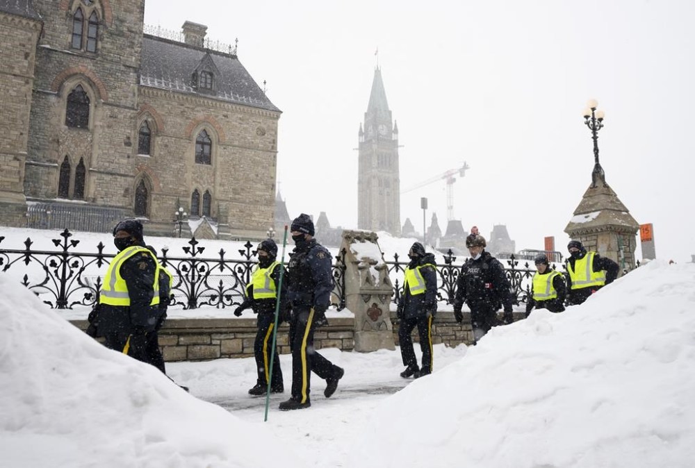 Police officers walk pass the Parliament buildings after a protest in Ottawa on Sunday, Feb. 20, 2022. The inquiry into Ottawa's unprecedented use of the Emergencies Act during protests in February will start its public hearings next month. The Public Order Emergency Commission announced today that it expects the hearings to run from Sept. 19 until Oct. 28 at Library and Archives Canada in downtown Ottawa. THE CANADIAN PRESS/Adrian Wyld