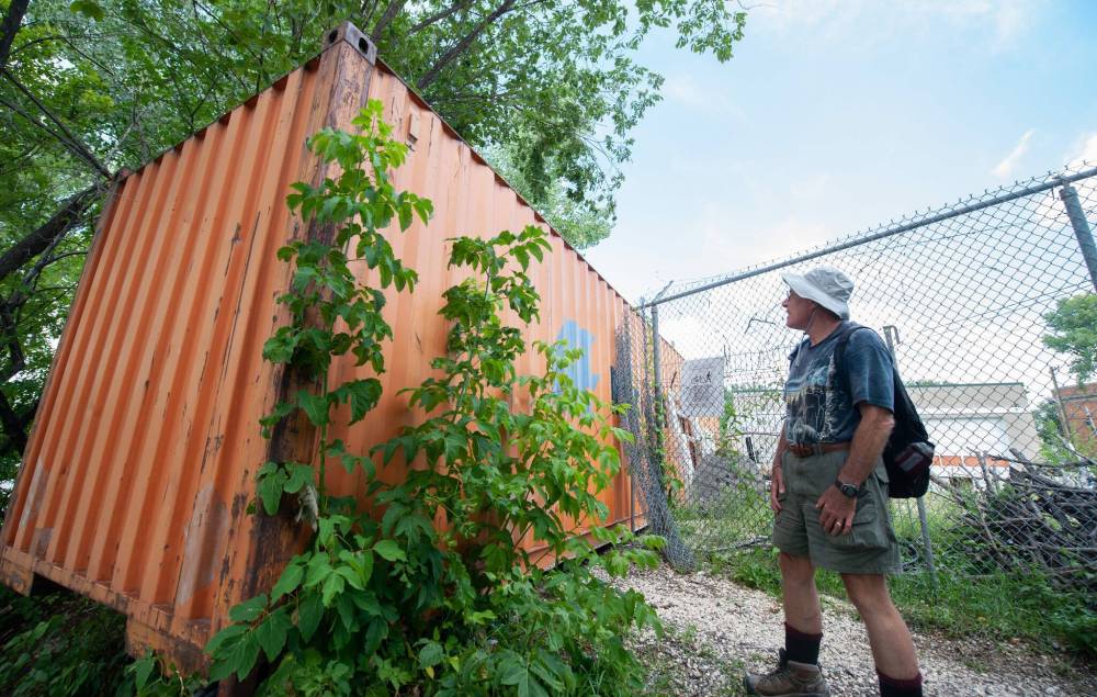 ETHAN CAIRNS / WINNIPEG FREE PRESS Avid hiker Mick Rice, 73, observes a shipping container blocking the trail wrapping behind Cladan Electric on Tache St. Part of the Whittier park trail system along the Red River in Winnipeg, Tuesday August 16, 2022
