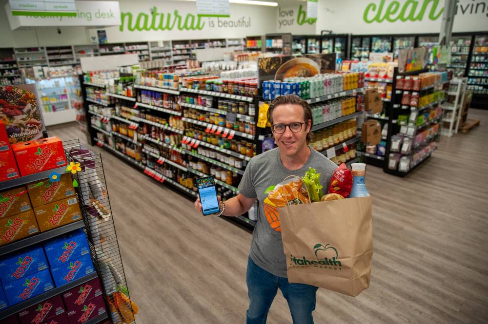 ETHAN CAIRNS / WINNIPEG FREE PRESS Mathew Holtmann, president of Vita Health, holds up a surprise bag of food and the Too Good to Go app.