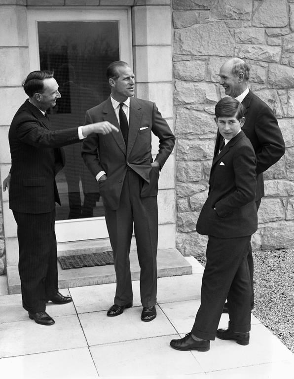 FILE - In this May 1, 1962 file photo, Britain's Prince Charles, tours his new school, Gordsonstoun, near Elgin, Scotland with his father, Prince Philip, as he arrives to start his first term. At left is house Master Robert Whitby, and Headmaster Mr. Robert Chew at right. Prince Charles has been preparing for the crown his entire life. Now, that moment has finally arrived. Charles, the oldest person to ever assume the British throne, became king on Thursday Sept. 8, 2022, following the death of his mother, Queen Elizabeth II. (AP Photo/File)