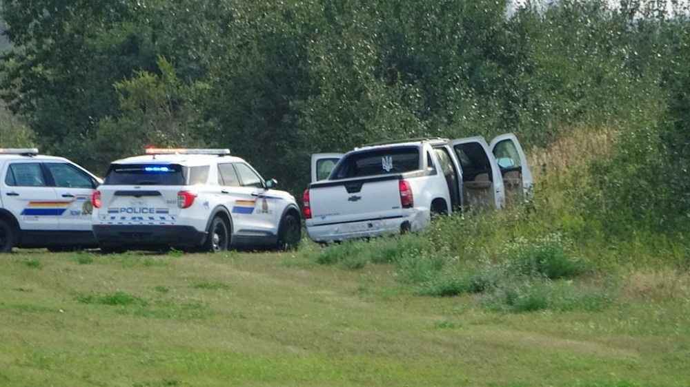 Police and investigators are seen at the side of the road outside Rosthern, Sask., on Wednesday, Sept. 7, 2022. In late spring, a parole officer issued an arrest warrant for Myles Sanderson, a Saskatchewan man with a violent past who had recently been released from prison. THE CANADIAN PRESS/Kelly Geraldine Malone