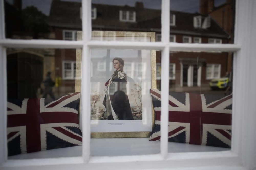 A portrait of Queen Elizabeth II is seen in a shop window, Monday, Sept. 12, 2022 in Windsor, England. Queen Elizabeth II, Britain's longest-reigning monarch and a rock of stability across much of a turbulent century, died Thursday Sept. 8, 2022, after 70 years on the throne. She was 96. (AP Photo/Christophe Ena)