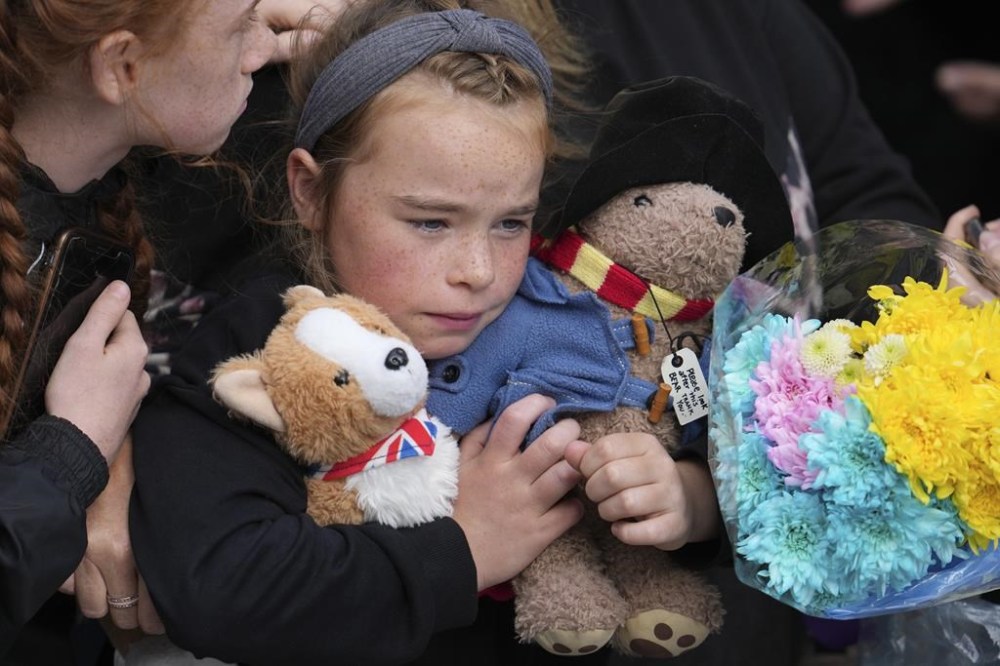 A young girl holds a Paddington bear and a Corgi dog stuffed toys while waiting to watch the Procession of Queen Elizabeth's coffin from the Palace of Holyroodhouse to St Giles Cathedral on the Royal Mile in Edinburgh, Scotland, Monday, Sept. 12, 2022. At the Cathedral there will be a Service to celebrate the life of the Queen and her connection to Scotland. (AP Photo/Jon Super, Pool)