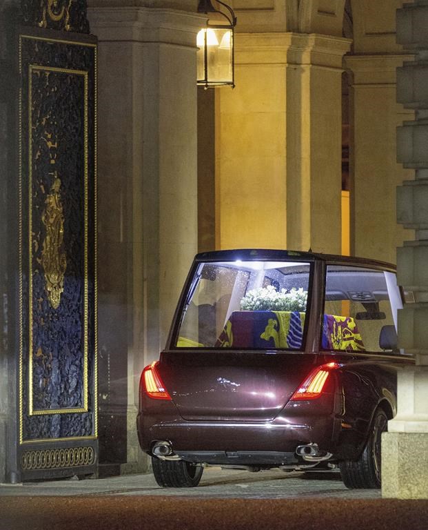 The hearse carrying the coffin of Queen Elizabeth II arrives at Buckingham Palace, in London, where it will rest overnight in the Bow Room, Tuesday, Sept. 13, 2022. (Suzan Moore/Pool Photo via AP)