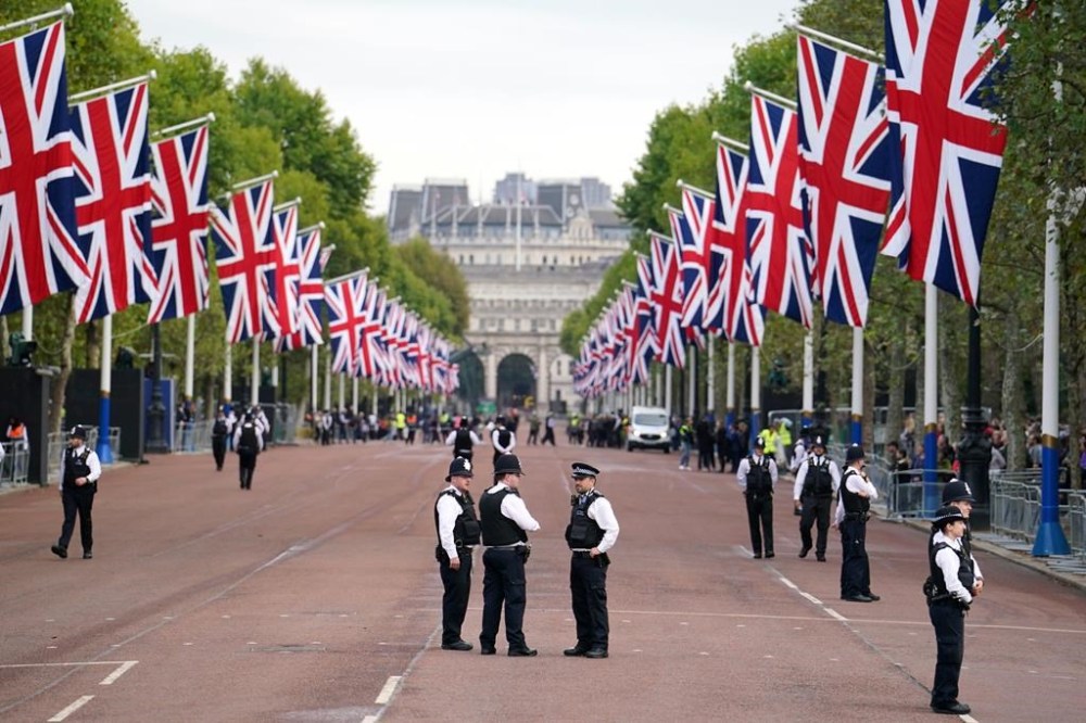 Police officers stand guard on The Mall ahead of the ceremonial procession of the coffin of Queen Elizabeth II, from Buckingham Palace to Westminster Hall, in London, Wednesday Sept. 14, 2022. The Queen will lie in state in Westminster Hall for four full days before her funeral on Monday Sept. 19. (Dominic Lipinski/PA via AP)