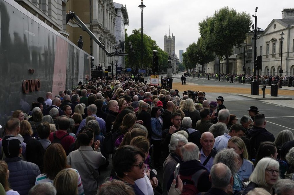 People gather along for the procession of the coffin of Queen Elizabeth II from Buckingham Palace to Westminster Hall, in London, Wednesday Sept. 14, 2022. Queen Elizabeth II, Britain's longest-reigning monarch and a rock of stability across much of a turbulent century, died Thursday Sept. 8, 2022, after 70 years on the throne. She was 96. (AP Photo/Kin Cheung)