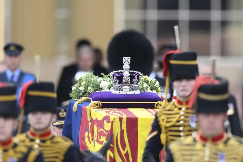 A view of the coffin of Queen Elizabeth II, adorned with a Royal Standard and the Imperial State Crown and pulled by a Gun Carriage of The King's Troop Royal Horse Artillery, during a procession from Buckingham Palace to Westminster Hall in London, Wednesday, Sept. 14, 2022. The Queen will lie in state in Westminster Hall for four full days before her funeral on Monday Sept. 19. (Daniel Leal/Pool Photo via AP)