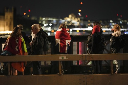 A woman draped with a Union flag waits with other people in the queue near Westminster Palace to pay their respect to the late Queen Elizabeth II during the Lying-in State, at Westminster Hall in London, Thursday, Sept. 15, 2022. The Queen will lie in state in Westminster Hall for four full days before her funeral on Monday Sept. 19. (AP Photo/Markus Schreiber)
