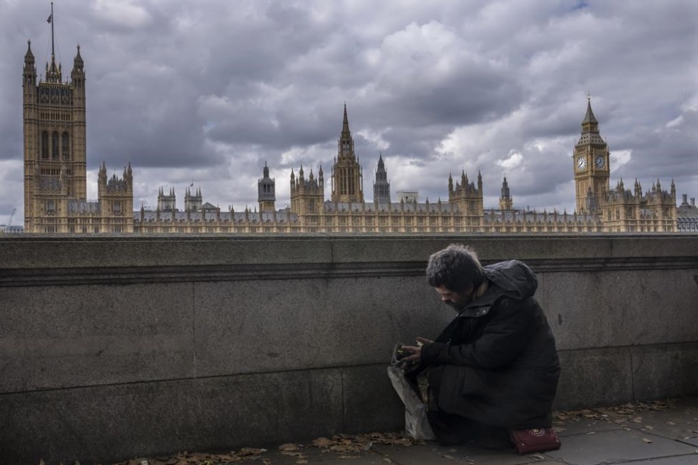A homeless man rests in a queue with people waiting to pay their respects to the late Queen Elizabeth II during the Lying-in State, outside Westminster Hall in London, Thursday, Sept. 15, 2022. The Queen will lie in state in Westminster Hall for four full days before her funeral on Monday Sept. 19.(AP Photo/Nariman El-Mofty)