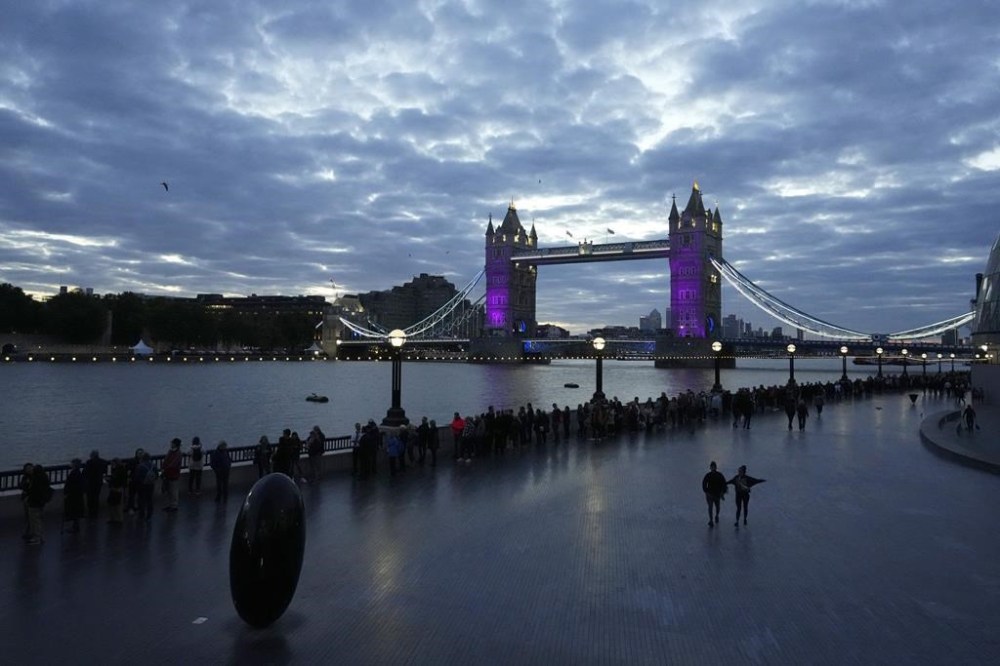 People walk in a queue past the Tower Bridge to pay their respect to the late Queen Elizabeth II during the Lying-in State, in Westminster Hall, in London, England, Friday, Sept. 16, 2022. The Queen will lie in state in Westminster Hall for four full days before her funeral on Monday Sept. 19. (AP Photo/Petr David Josek)