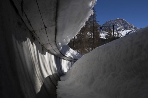 FILE - The bobsled track in Cortina d'Ampezzo, Italy, is shown on Feb. 17, 2021. Costly construction delays, a leadership vacancy linked to a volatile political climate and a lack of sponsors amid a spreading financial crisis has prompted International Olympic Committee president Thomas Bach to acknowledge the 