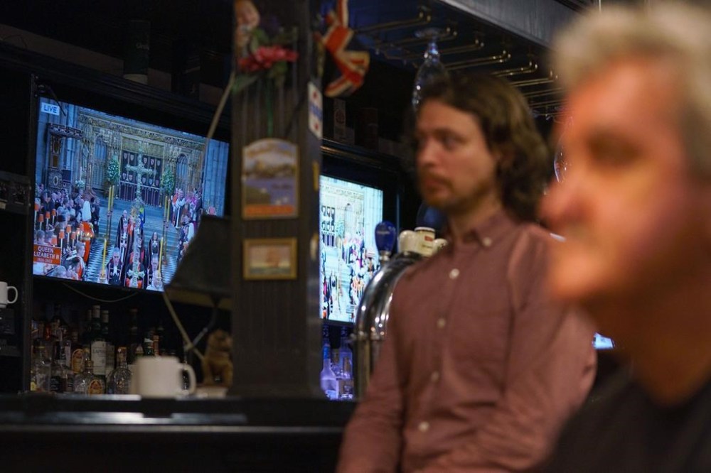 People watch the funeral of Queen Elizabeth on television screens at The Bishop and Belcher pub in Toronto on the morning of Monday, Sept. 19, 2022. Moments of silence and other tributes are set to be held for Queen Elizabeth II across Ontario this afternoon. THE CANADIAN PRESS/Alex Lupul