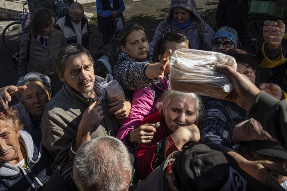 Local residents receive humanitarian aid distributed by volunteers in the recently retaken area of Izium, Ukraine, Wednesday, Sept. 21, 2022. (AP Photo/Evgeniy Maloletka)