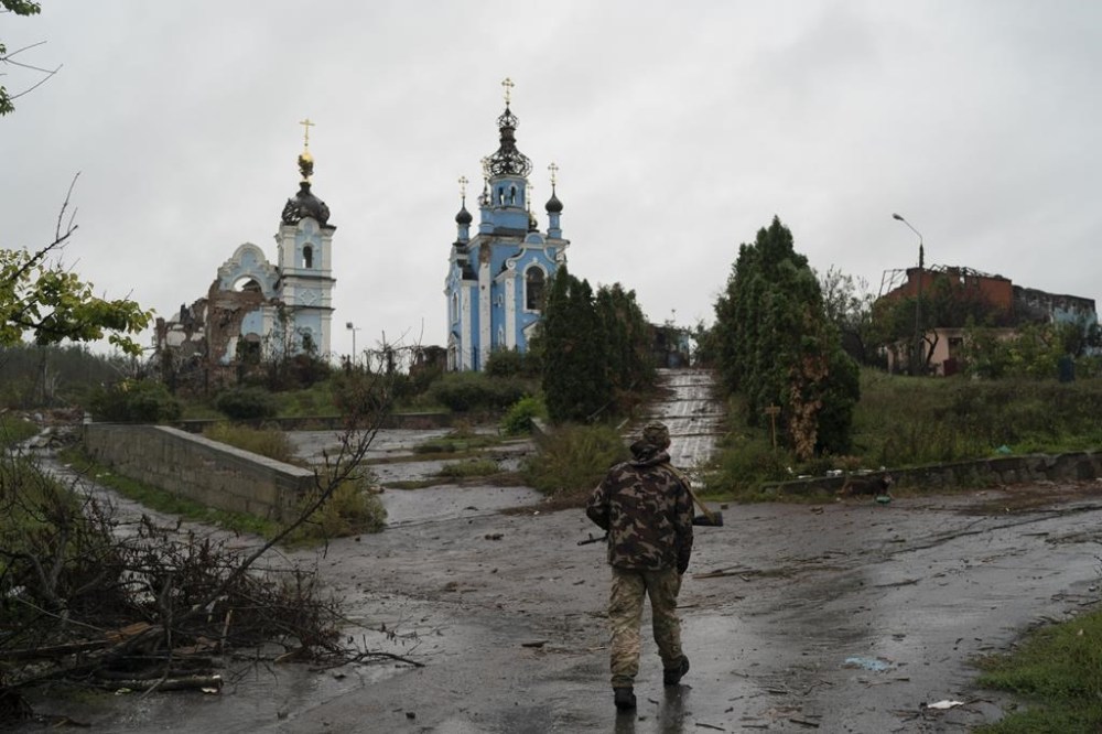 A Ukrainian serviceman walks past heavily damaged church in the retaken village of Bohorodychne, eastern Ukraine, Friday, Sept. 23, 2022. (AP Photo/Leo Correa)