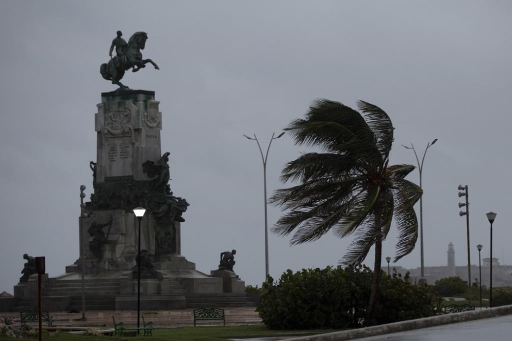 Wind blows a palm tree at the Antonio Maceo Monument along the malecon sea wall during the passing of Hurricane Ian in Havana, Cuba, early Thursday, Sept. 27, 2022. (AP Photo/Ismael Francisco)