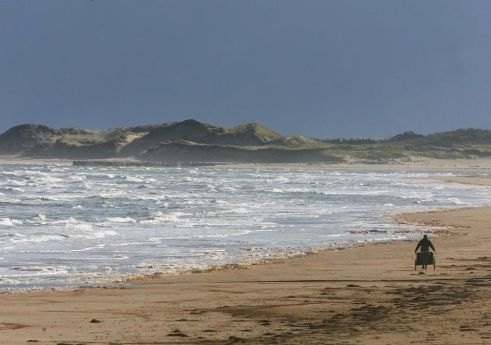 An unidentified man pulls a hand cart along the beach in Prince Edward Island National Park, near Stanhope, on Friday, Oct. 25, 2002. Parks Canada says the scale of sand dune erosion at beaches in Prince Edward Island National Park due to post-tropical storm Fiona is “shocking.” THE CANADIAN PRESS/Andrew Vaughan