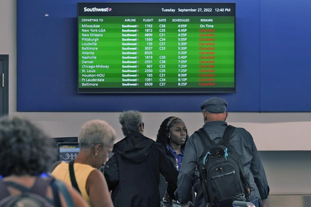 Southwest Airline passengers check into a ticket counter near a sign that shows canceled flights at the Tampa International Airport Tuesday, Sept. 27, 2022, in Tampa, Fla. The airport is closing at 5pm EST today ahead of Hurricane Ian. Ian is predicted to make landfall somewhere along Florida's west coast. (AP Photo/Chris O'Meara)