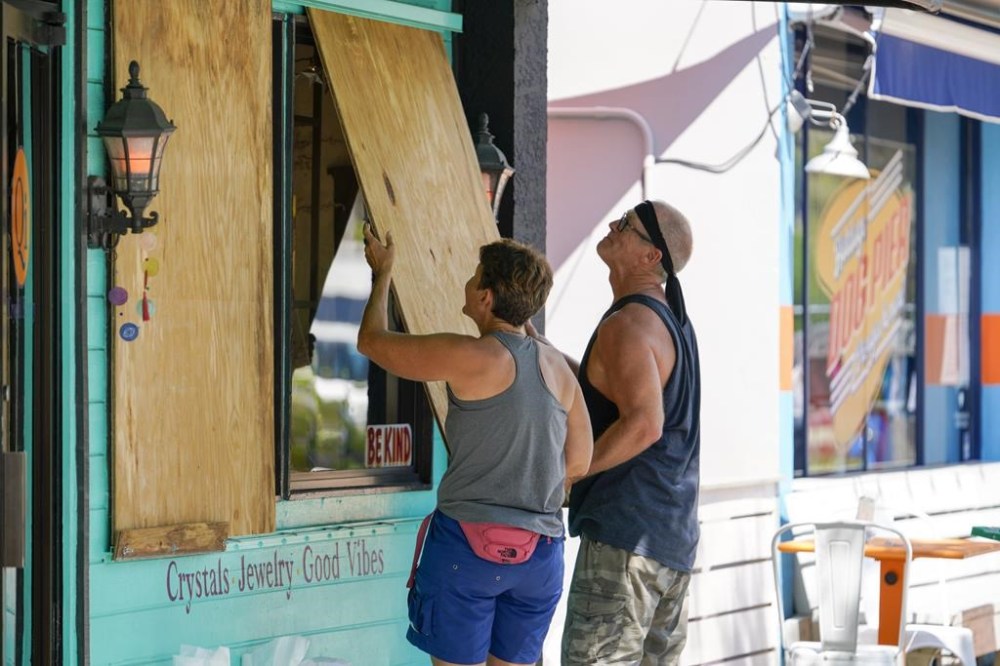 FILE - Lisa Bromfield and Mike Sernett work to place a sheet of plywood on the front windows of a store in downtown Gulfport in preparation for the arrival of Hurricane Ian, Sept. 26, 2022, in South Pasadena, Fla. Hurricane Ian is quickly gaining monstrous strength as it moves over oceans partly heated up by climate change. (Martha Asencio-Rhine/Tampa Bay Times via AP, File)