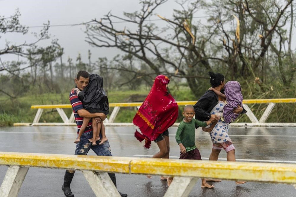 A family walks in the rain after Hurricane Ian hit Pinar del Rio, Cuba, Tuesday, Sept. 27, 2022. Ian made landfall at 4:30 a.m. EDT Tuesday in Cuba’s Pinar del Rio province, where officials set up shelters, evacuated people, rushed in emergency personnel and took steps to protect crops in the nation’s main tobacco-growing region. (AP Photo/Ramon Espinosa)