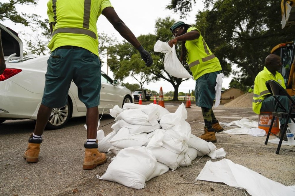 City employees load sandbags into people's cars as they pull up to a station at Northwest Park, in preparation for Hurricane Ian, Tuesday, Sept. 27, 2022, in St. Petersburg, Fla. (Martha Asencio-Rhine/Tampa Bay Times via AP)