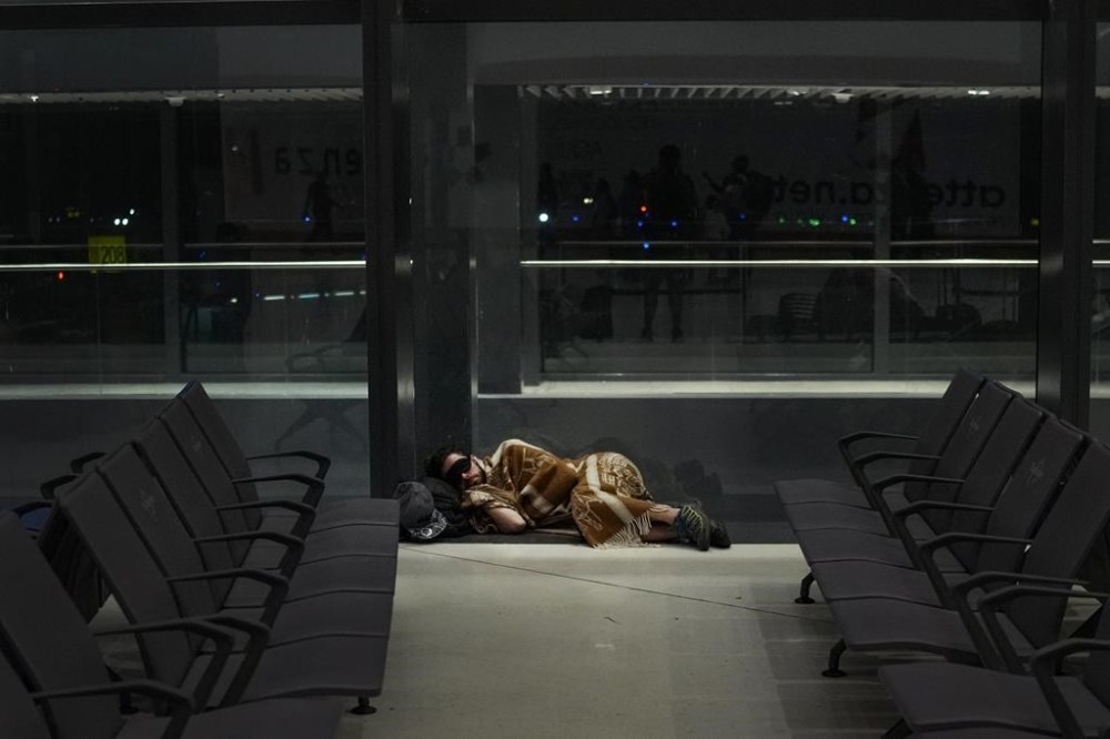 A passenger sleeps on the floor after his flight was delayed due to Hurricane Ian, at Tocumen International Airport in Panama City, Tuesday, Sept. 27, 2022. Hurricane Ian tore into western Cuba as a major hurricane and left 1 million people without electricity, then churned on a collision course with Florida over warm Gulf waters amid expectations it would strengthen into a catastrophic Category 4 storm. (AP Photo/Matias Delacroix)
