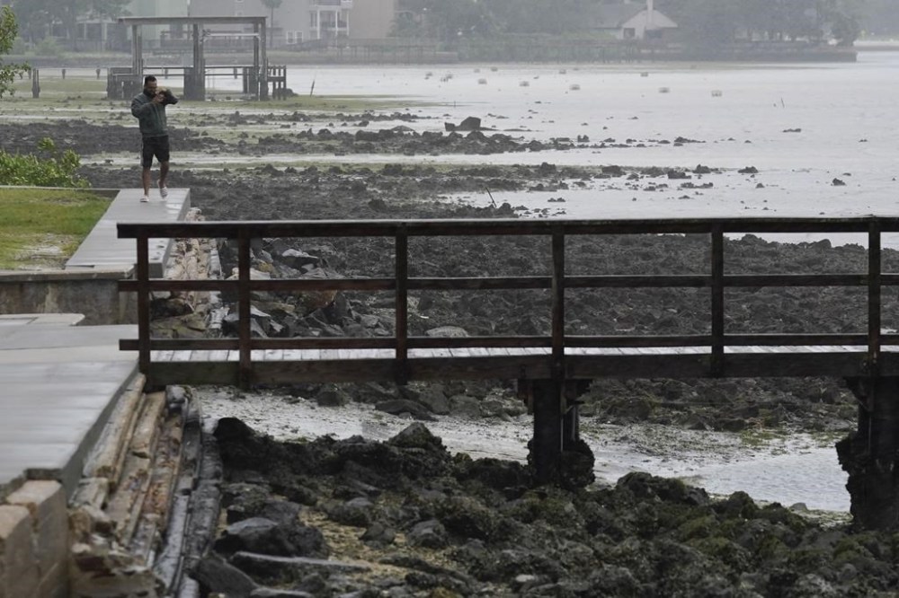 A man walks near Ballast Point Pier as water moves away from shore as Hurricane Ian begins to move into the area, Wednesday, Sept. 28, 2022, in , Fla. (AP Photo/Chris O'Meara)