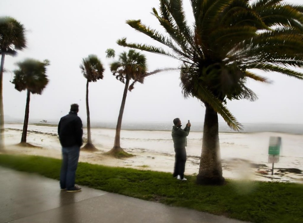 Bob Burnett, 77, looks on as his son Bobby Burnett, 42, takes pictures of the pier as Tampa Bay is draining in a reverse storm surge with Hurricane Ian expected to make landfall this afternoon on Wednesday, Sept. 28, 2022 in St. Petersburg, Fla. Hurricane Ian rapidly intensified as it neared landfall along Florida's southwest coast Wednesday morning, gaining top winds of 155 mph (250 kph), just shy of the most dangerous Category 5 status. (Dirk Shadd/Tampa Bay Times via AP)
