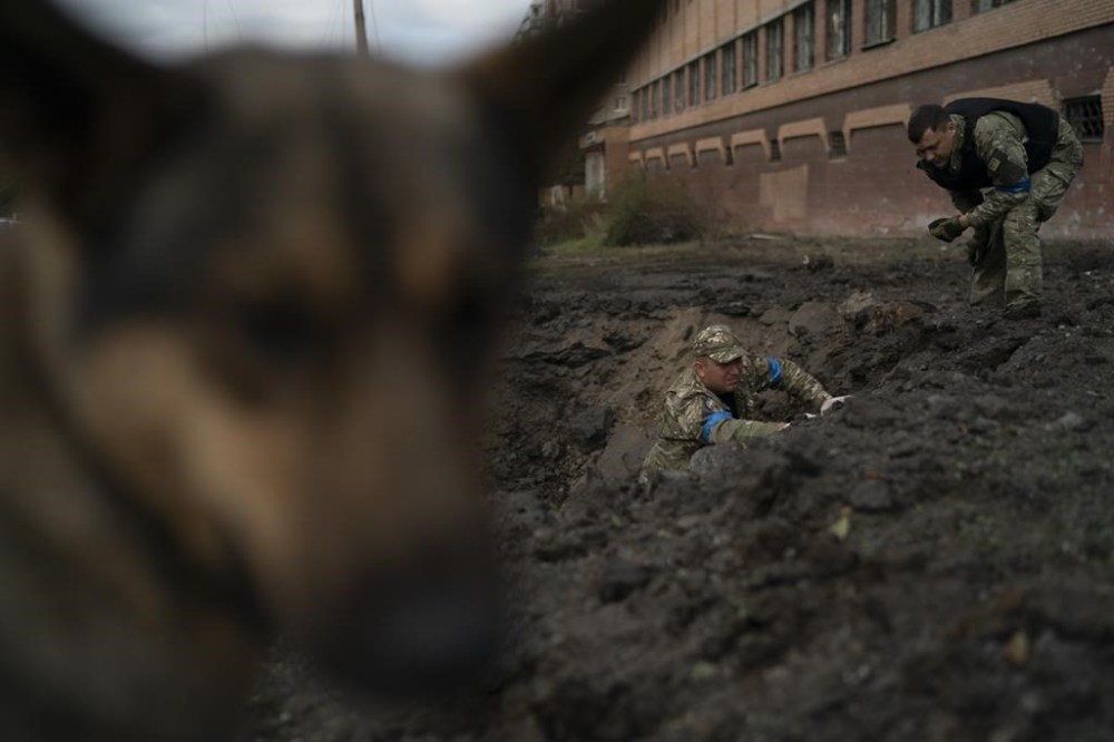 Ukrainian police officers collect fragments from a crater to determine the type of ammunition after a Russian attack in Kramatorsk, Ukraine, Thursday, Sept. 29, 2022. (AP Photo/Leo Correa)
