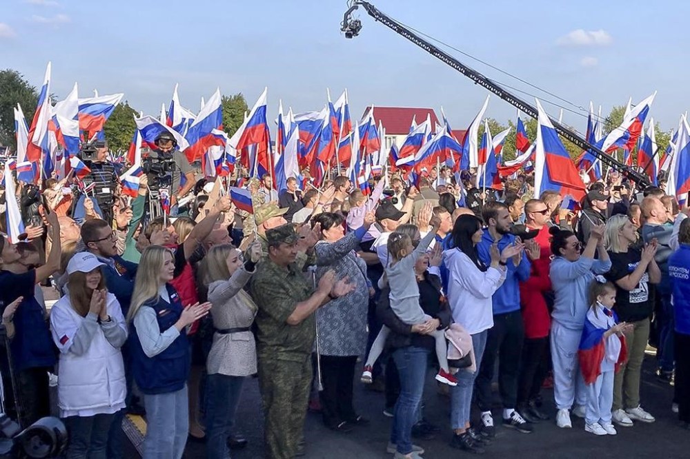 People react during celebrations marking the incorporation of the Donetsk region into Russia in Donetsk, Ukraine, Friday, Sept. 30, 2022. The signing of the treaties making the four regions part of Russia follows the completion of the Kremlin-orchestrated