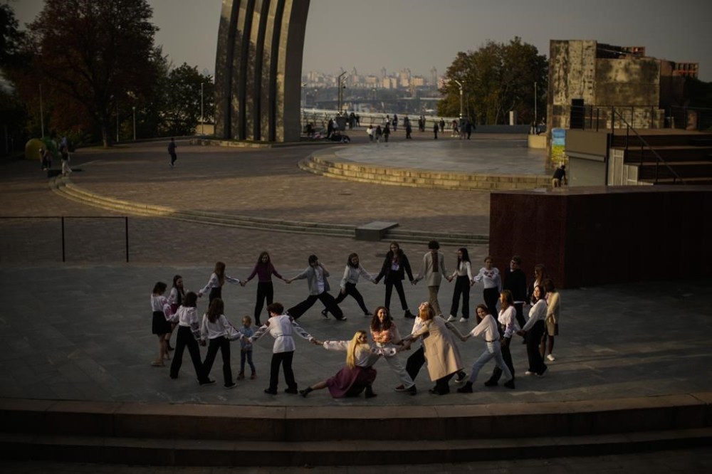 Youngsters play a group game at the Arch of Freedom of the Ukrainian people square in Kyiv, Ukraine, Friday, Sept. 30, 2022. (AP Photo/Francisco Seco)