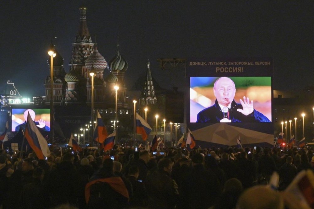 People watch on a large screen, as Russian President Vladimir Putin speaks during celebrations marking the incorporation of regions of Ukraine to join Russia, at the Red Square in Moscow, Russia, Friday, Sept. 30, 2022. The signing of the treaties making the four regions part of Russia follows the completion of the Kremlin-orchestrated