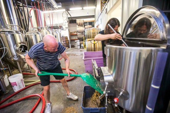 Ben Sigurdson (left) and Nonsuch head brewer Mark Borowski clean out leftover malt from the tank while brewing After Deadline. (Mikaela MacKenzie / Winnipeg Free Press)