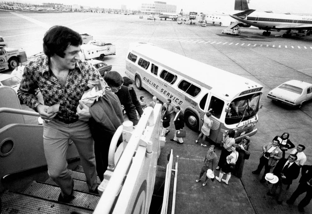 BARRIE DAVIS / THE GLOBE AND MAIL FILES
SEPTEMBER 12, 1972 — TORONTO — TEAM CANADA LEAVES FOR EUROPE — Team Canada players at Toronto airport Sept. 12, 1972 where they will head to Russia via Sweden for the final half of the Canada-Russia Summit Series. Centre Phil Espositon looks back at well-wishers as he climbs stairs towards aircraft that will fly the team to Europe.