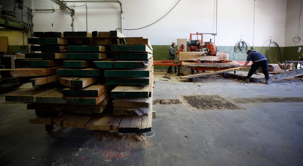 Employee Zach Rogers clears the cut lumber while Jesse Marr operates a milling machine.