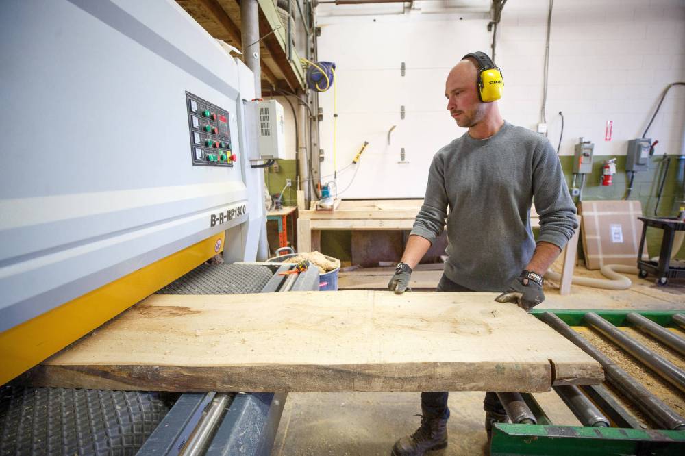 McGarry puts a plank through a planing machine to take out the blade marks from the milling machine.