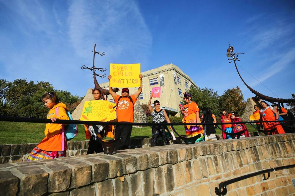 Gerald Abraham, whose traditional name is Blackcloud, from Little Black River First Nation holds up a sign that says, ”Every Child Matters” as he enters the Oodena Celebration Circle Friday morning. (Mike Deal / Winnipeg Free Press)
