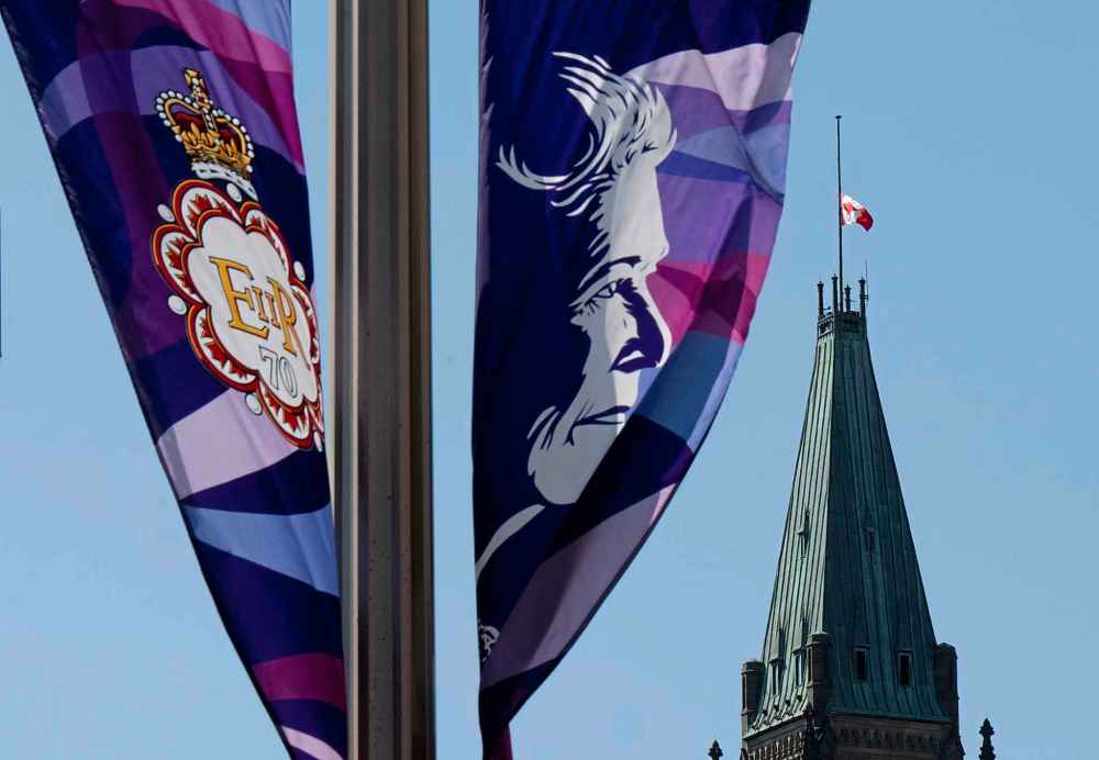 Banners from the Queen's Platinum Jubilee fly on a lamp post as the flag on Parliament Hill flies at half mast to recognize her death Thursday, Sept. 8, 2022 in Ottawa. THE CANADIAN PRESS/Adrian Wyld