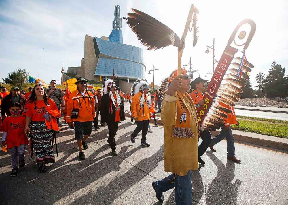 People pass the Canadian Museum for Human Rights during the annual Orange Shirt Day Survivors Walk and Pow Wow on National Day for Truth and Reconciliation in Winnipeg. (John Woods / The Canadian Press)