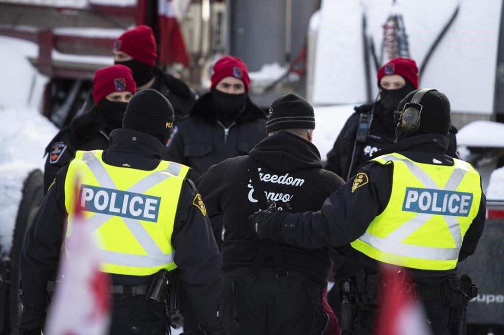 A trucker is led away after leaving his truck as police aim to end an ongoing protest against COVID-19 measures that has grown into a broader anti-government protest, on its 22nd day, in Ottawa, on Friday, Feb. 18, 2022. A former senior Ontario Provincial Police officer says early meetings between Ottawa police officials and experts sent by other agencies to help were